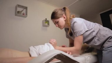 Kadın masör terapist, sağlıklı ayak masajı yapıyor profesyonel terapi ellerini yağlıyor. Kanepe masasında uzanan kız masaj salonu vücut bakımı konseptini yavaş çekimde tedavi görüyor.