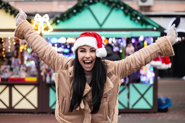 きれいな笑みを浮かべて口を白い歯の女性は暖かいコート笑い叫んで服を着て祝うジェスチャー 寒い天候 冬の市場の休日の公正 旅行リゾート 新年の帽子クリスマスの装飾 — ストック写真
