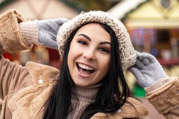 年轻漂亮的微笑着张开嘴 洁白的牙齿女人摆出喜庆的架势 穿上温暖的外套笑了 寒冷的天气 冬季市场假期的集市 旅游精神度假胜地 新年装饰品 — 图库照片