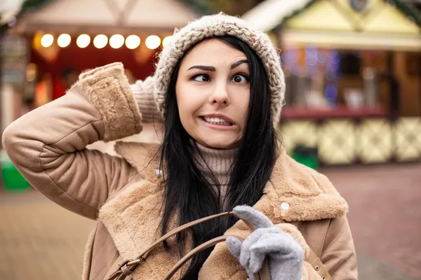 若いかわいい女性は 暖かいコートのミトンを祝うことをジェスチャー顔の顔をグリームを作る 寒い天候 冬の市場の休日の公正 旅行精神リゾート 新年のクリスマス飾り — ストック写真