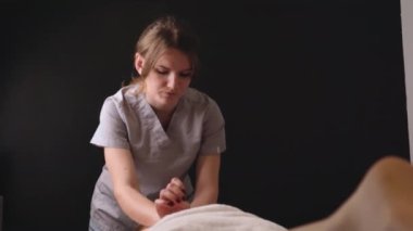 Kadın masör terapist sağlıklı sırt masajı yapıyor profesyonel terapi ellerini yağlıyor. Kanepe masasında uzanan kız güzellik salonunda vücut bakımı konseptinde masaj yaptırıyor, yavaş çekimde tedavi oluyor.