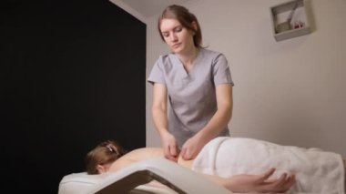 Kadın masör terapist sağlıklı sırt masajı yapıyor profesyonel terapi ellerini yağlıyor. Kanepe masasında uzanan kız güzellik salonunda vücut bakımı konseptinde masaj yaptırıyor, yavaş çekimde tedavi oluyor.