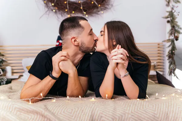Bella Giovane Coppia Romantica Sdraiata Ghirlande Letto Abbracciare Baciare Casa — Foto Stock