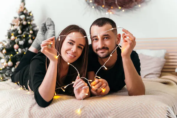 Encantador Jovem Casal Romântico Deitado Cama Guirlandas Abraçando Casa Atmosfera — Fotografia de Stock