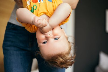 Küçük tatlı çocuk kızıl saçlı bebek hafta sonunu babasıyla baş aşağı takılarak geçiriyor. Bebek evde oyuncakları tutarken eğleniyor. Mutlu çocukluk, aile aşkı kavramı
