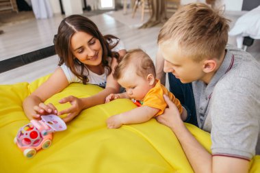 Küçük tatlı çocuk kızıl saçlı bebek hafta sonu ailesiyle birlikte yerde vakit geçiriyor. Bebek evde el ele tutuşarak eğleniyor. Mutlu çocukluk, aile aşkı kavramı