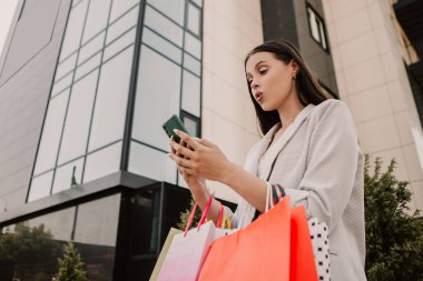 Shocked lady hold hands many bags and phone shopper woman dressed plaid blazer carrying enjoying new clothes packs things after shopping buyings sales black friday concept