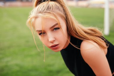 Woman standing on the football stadium with green grass or lawn. Lady tired exhausted after running treadmill productive workout. Female dressed sportswear, health care concept