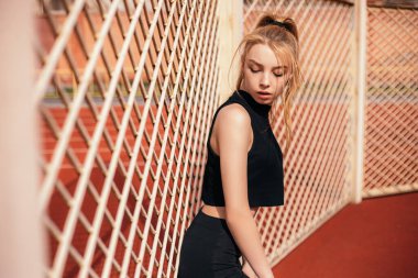 Woman standing relaxing outside after cardio training outside stadium in the morning. Athletic lady dressed fitness sportwear. Healthy lifestyle, sport and recreation concept.