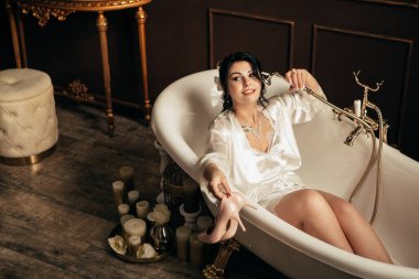 Stüdyodaki fotoğraf çekiminde eşi. Evli gelin nişanı kutluyor. Üreme romantik inanılmaz kadın kapalı, kopyalama alanı. Düğün gününe hazırlanıyorum, banyoda yatıyorum ve topuklu ayakkabı tutuyorum.