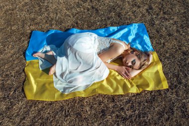 Ukrayna sarısı mavi bayrağında yatan kadın portresi. Ukrayna 'nın ulusal sembolü. Makyajlı vatansever kadın sahada yürüyor. Ukrayna, destek ve dayanışma