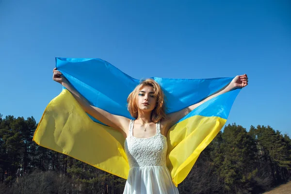 Ukrayna sarısı mavi bayrağa sarılı kadın portresi rüzgarda dalgalanıyor. Ukrayna 'nın ulusal sembolü. Makyajlı vatansever kadın. Ukrayna, destek ve dayanışma