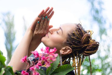 Bahçede ya da şehir parkında çiçeklerin yanında duran rastalı yoga yapan kadın. Sabahları dinleniyorum.. 