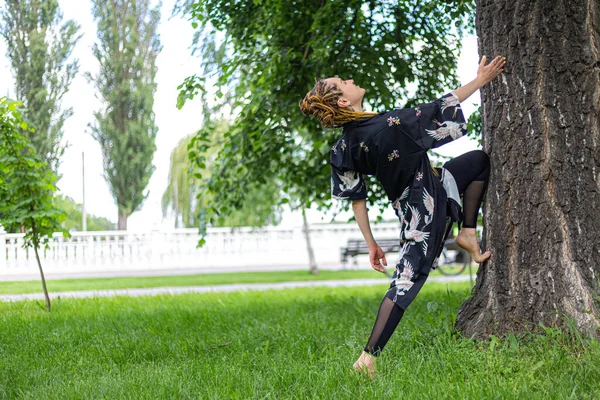 Rastalı Yoga Yapan Esneyen Yeşil Çimlerde Poz Veren Bir Kadın — Stok fotoğraf