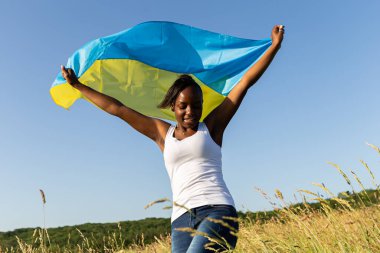 Ukrayna sarısı mavi bayrağa sarılmış Afro-Amerikalı kadın rüzgarda dalgalanıyor. Ukrayna 'nın ulusal sembolü. Ukrayna, uluslararası destek ve dayanışma