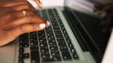 Close up shot african american woman sitting outside using laptop in cafe, typing message on keyboard. Freelancer business lady working. Young entrepreneur making a deal in the internet
