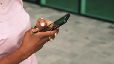 African american woman standing outside street using mobile phone smartphone, typing message. Freelancer business lady working. Young entrepreneur making a deal in the internet