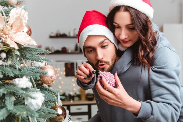 Lovely Young Romantic Couple Wear Red Hats Decorate Christmas Tree — Stockfoto