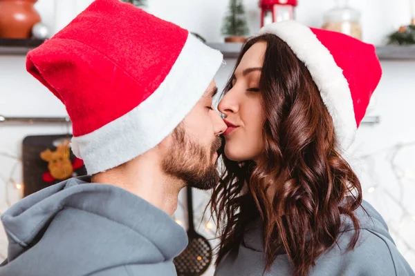 Lovely Young Romantic Couple Standing Kitchen Wear Red Hats Kissing — Stockfoto