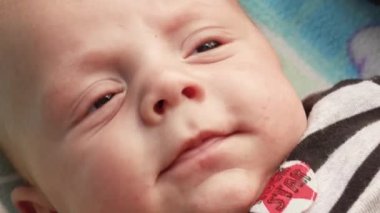 4K video kaydı. Bebek arabasında bebek arabasında uzanan, eğlenen, annesine bakan, gülümseyen yeni doğmuş bebeğe yakından bakın. Dışarıda sandalyede yürüyorum, temiz hava.