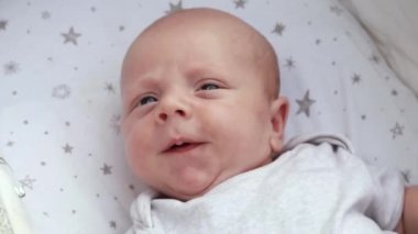 1080p yavaş çekim videosu. Bebek arabasında bebek arabasında uzanan, eğlenen, annesine bakan, gülümseyen yeni doğmuş bebeğe yakından bakın. Dışarıda sandalyede yürüyorum, temiz hava.