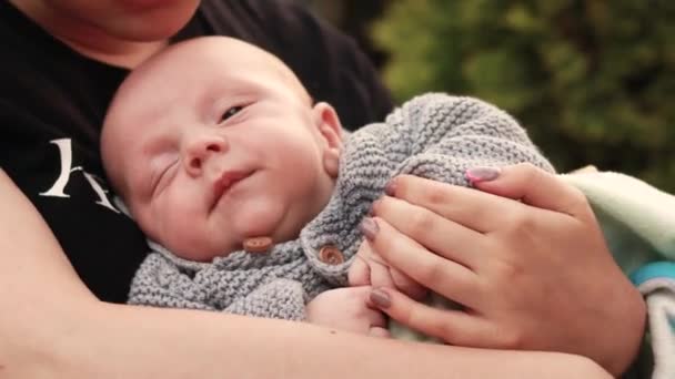 4K映像だ 閉じる母親の手を新生児の子供の楽しさを遊んで ニット暖かいセーターを着て 眠い幼児を保持睡眠したいと思った 外を歩くと新鮮な空気が — ストック動画