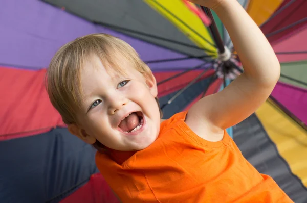 Lachen jongen onder kleurrijke paraplu. — Stockfoto