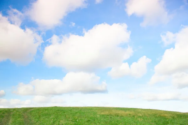 Bela paisagem com grama verde e nuvens no céu — Fotografia de Stock