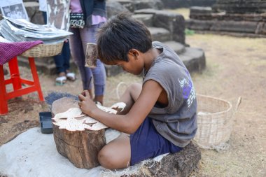 A child worker making the leather carving at Angkor wat. clipart