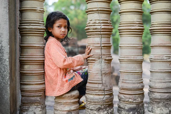 A shy girl sitting on a stone pillar. Angkor wat Temple, Siem Reap, Cambodia — Stock Photo, Image