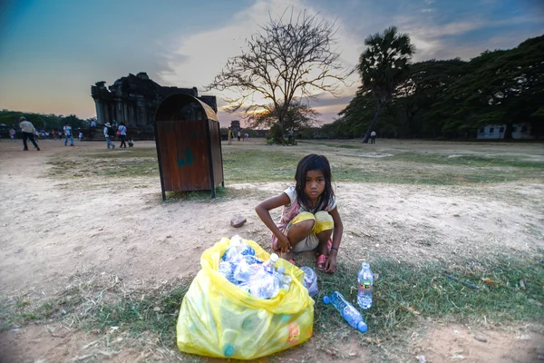 "Siem Reap, Cambodia - March 30, 2013 : A homeless Cambodian girl helps support her family by scavenging for empty bottles items that have been discarded on the angkor wat temple." Rechtenvrije Stockfoto's