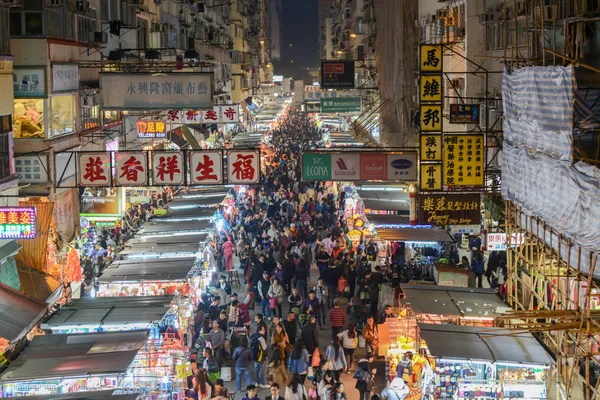 Уличные торговцы Фа Юэнь продают товары на дороге между зданиями. Он выложен одеждой, фруктами, игрушками и одеждой в гонконгском городе Монг Кок. . — стоковое фото