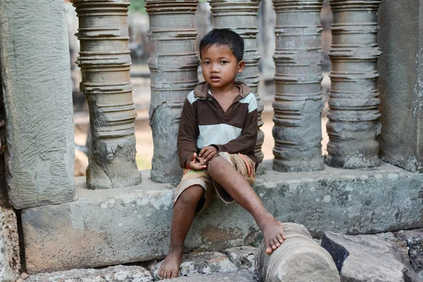 A shy boy sitting on a stone pillar — Stock Photo, Image