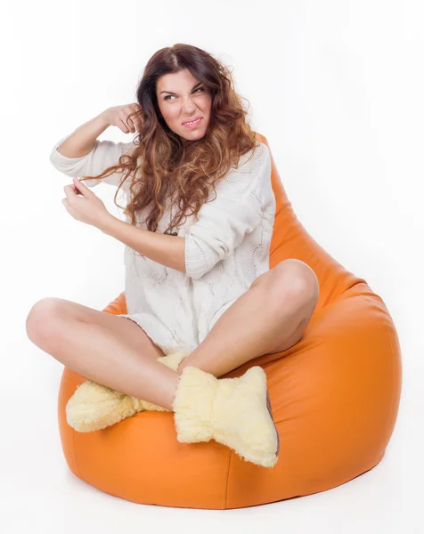 Schönes junges Mädchen sitzt auf dem orangefarbenen Kissen — Stockfoto