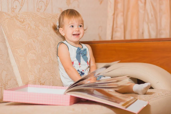Den lilla flickan överväger ett album med fotografier — Stockfoto