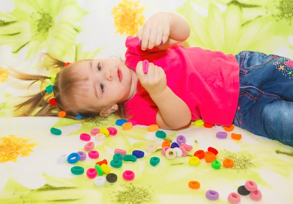 En liten flicka spelar med gummiband för hår — Stockfoto