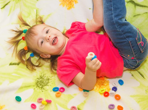 Uma menina brinca com elásticos para o cabelo sentado — Fotografia de Stock