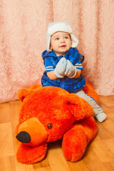 A little boy in winter hat sitting on the toy bears — Stock Photo, Image