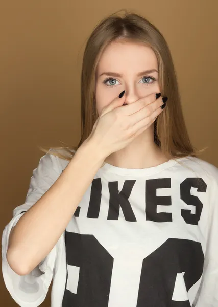 Ein junges Mädchen im T-Shirt schließt den Mund mit der Hand — Stockfoto