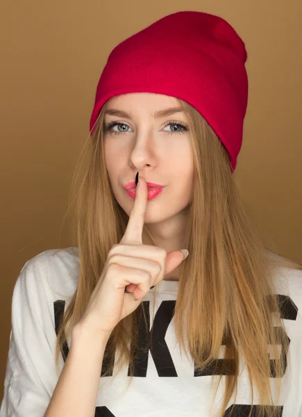 Mladá dívka teenager v čepici a tričko přiložil prst k jeho l — Stock fotografie