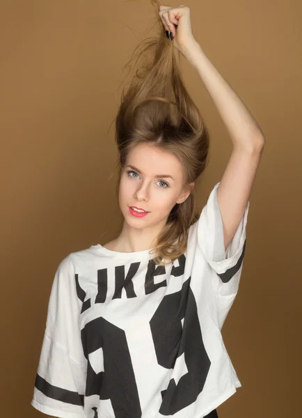 Uma jovem garota em uma camiseta brincando com o cabelo — Fotografia de Stock