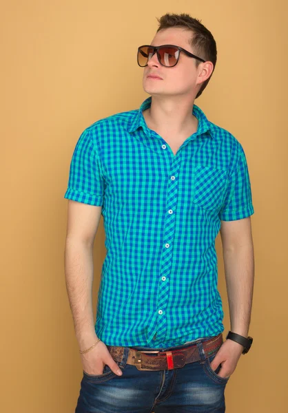 Beautiful guy in a shirt, jeans and sunglasses — Stock Photo, Image