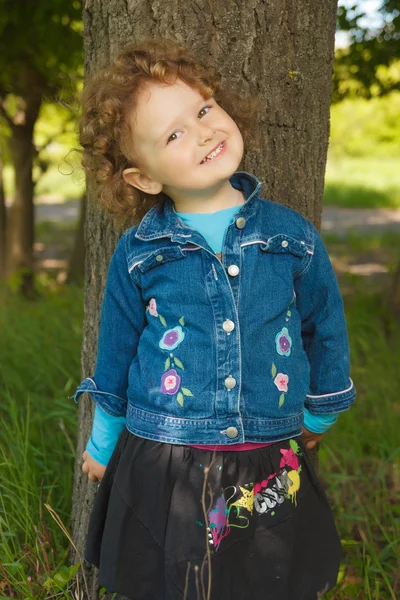 Trochę kręcone dziewczyna uśmiechając się w parku — Zdjęcie stockowe