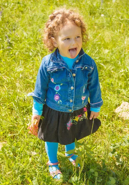 Lilla curly girl visar tungan — Stockfoto