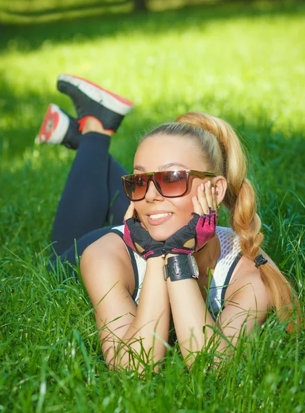 Schöne athletische Mädchen lächelnd auf dem Gras liegend — Stockfoto