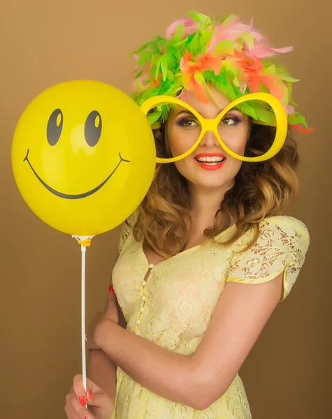 Beautiful girl in a bright wig and big glasses holding a balloon — Stock Photo, Image