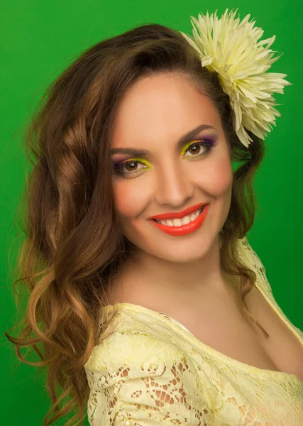 Красивая улыбающаяся девушка с ярким макияжем и цветочком — стоковое фото