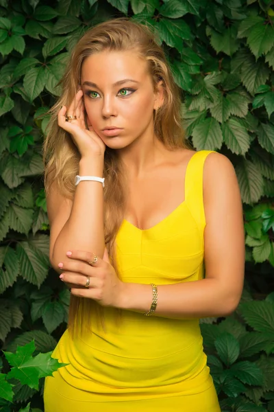 Schöne athletische Mädchen in einem gelben Kleid posiert auf einem Hintergrund — Stockfoto