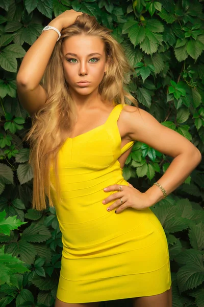 Schöne athletische Mädchen in einem gelben Kleid posiert auf einem Hintergrund — Stockfoto