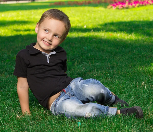 草の上に座っている笑顔の小さな男の子 — ストック写真